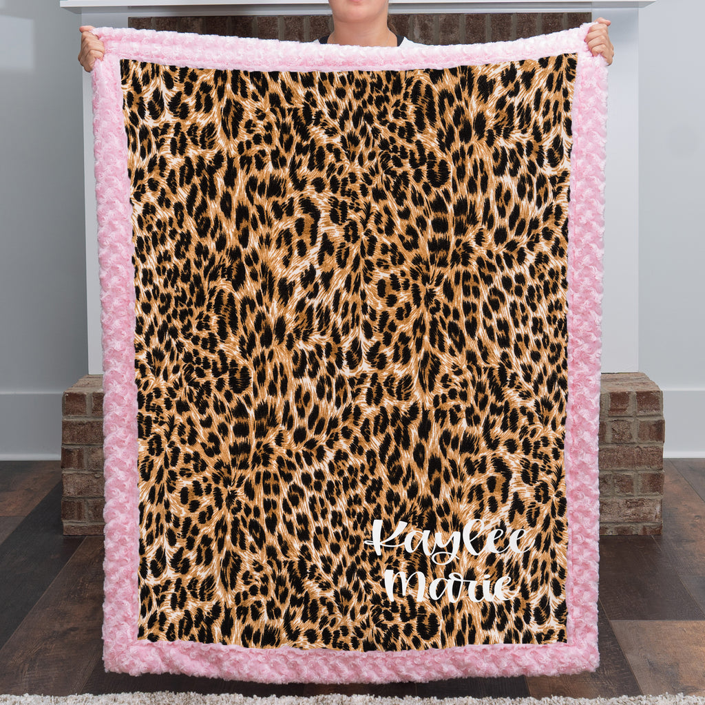Woman holding personalized leopard print minky blanket with pink trim