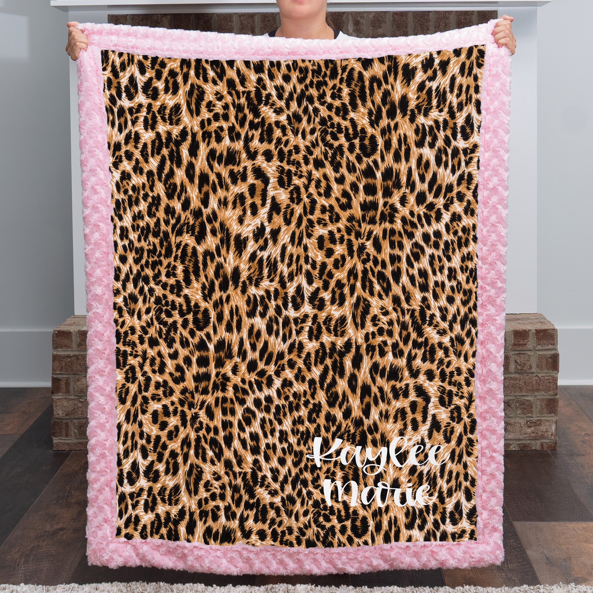 Woman holding personalized leopard print minky blanket with pink trim