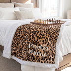 Personalized leopard print minky blanket with white sherpa back draped on bed with chess set