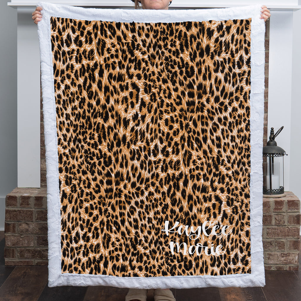 Woman holding personalized leopard print minky blanket with white trim