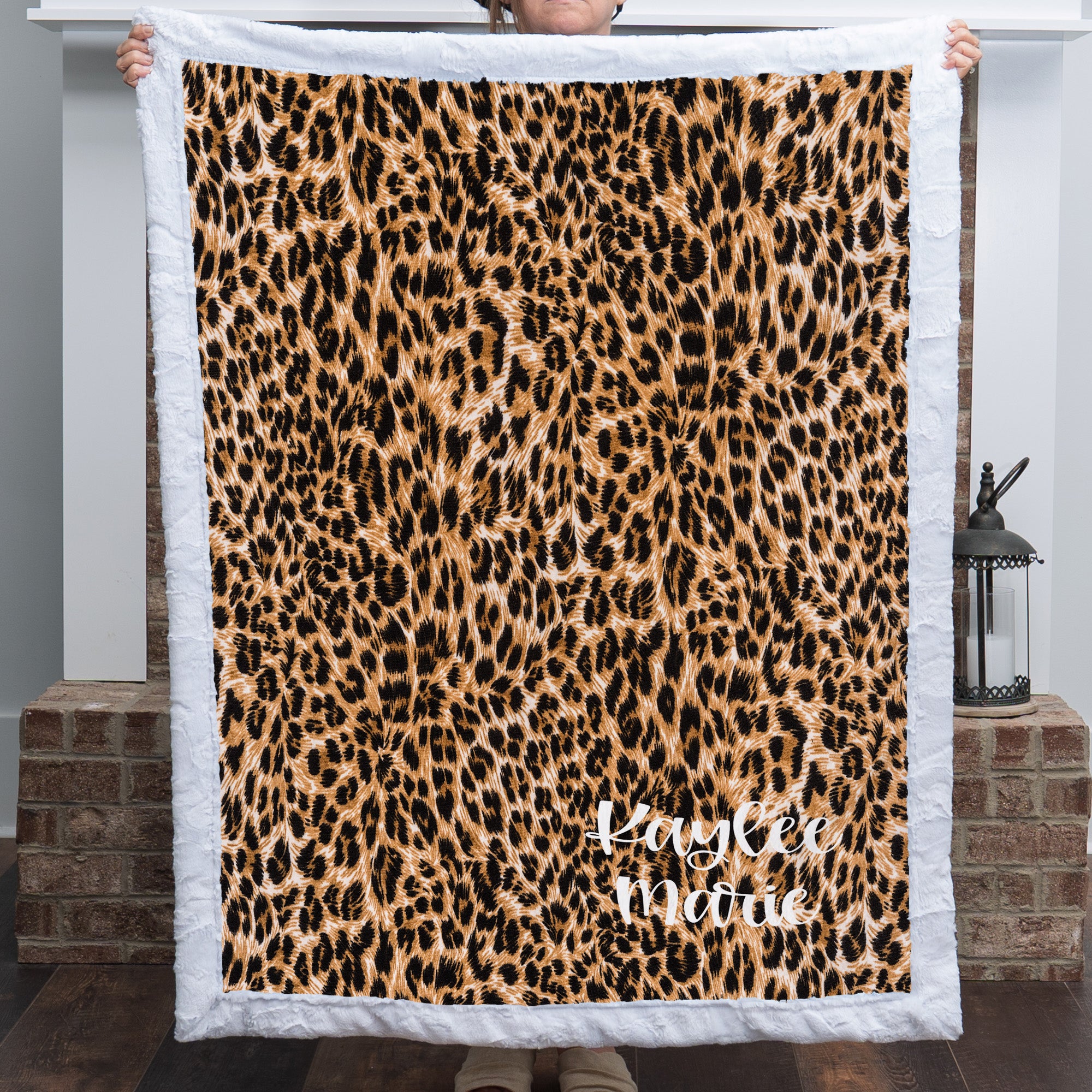Woman holding personalized leopard print minky blanket with white trim
