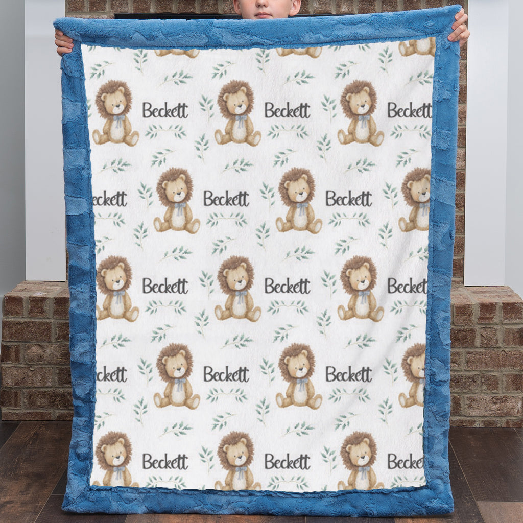 Child holding personalized minky lion baby blanket with blue fur border by brick fireplace