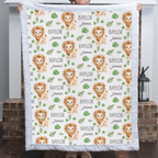 Personalized lion baby blanket with blue minky trim held up in cozy living room