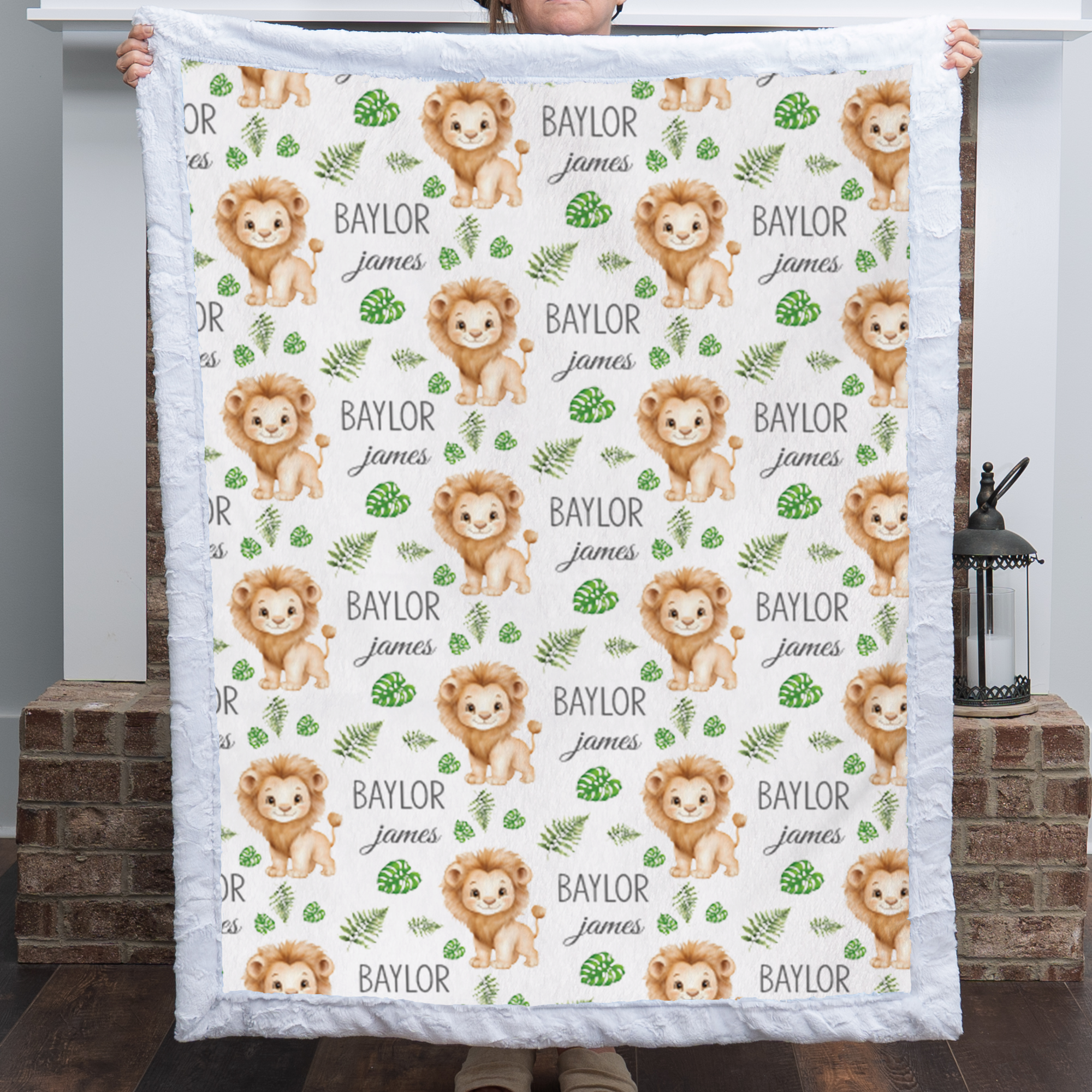 Personalized lion baby blanket with blue minky trim held up in cozy living room
