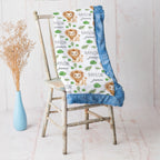 Lion print baby blanket with blue minky trim draped over vintage rustic chair