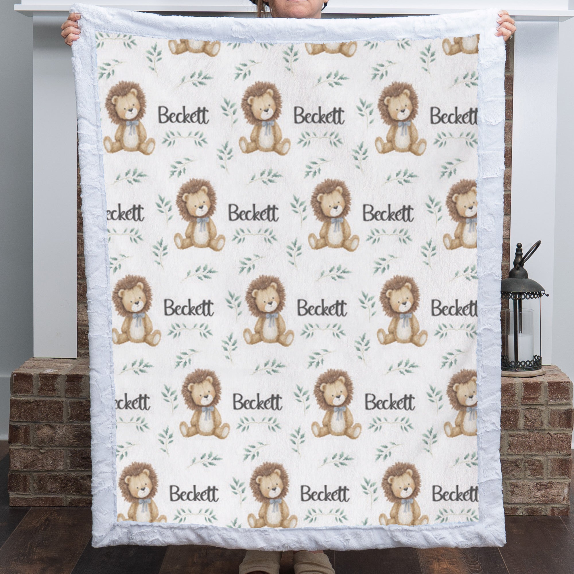 Personalized minky lion baby blanket with white fur border held up by fireplace with lantern