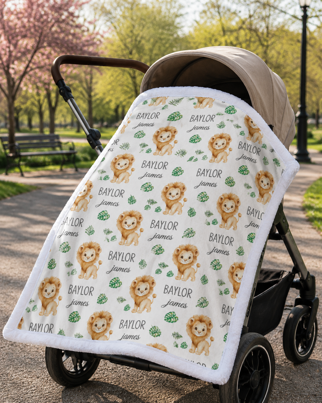 Personalized lion baby blanket with white minky trim draped over stroller in park