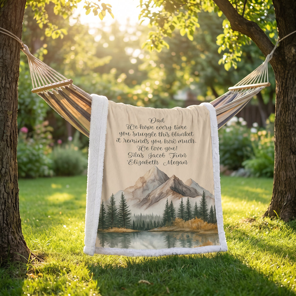 Personalized mountain lake blanket with a Dad message draped over a garden hammock in sunlight