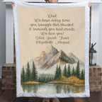 Personalized mountain lake blanket with a Dad message held up in front of a brick fireplace indoors