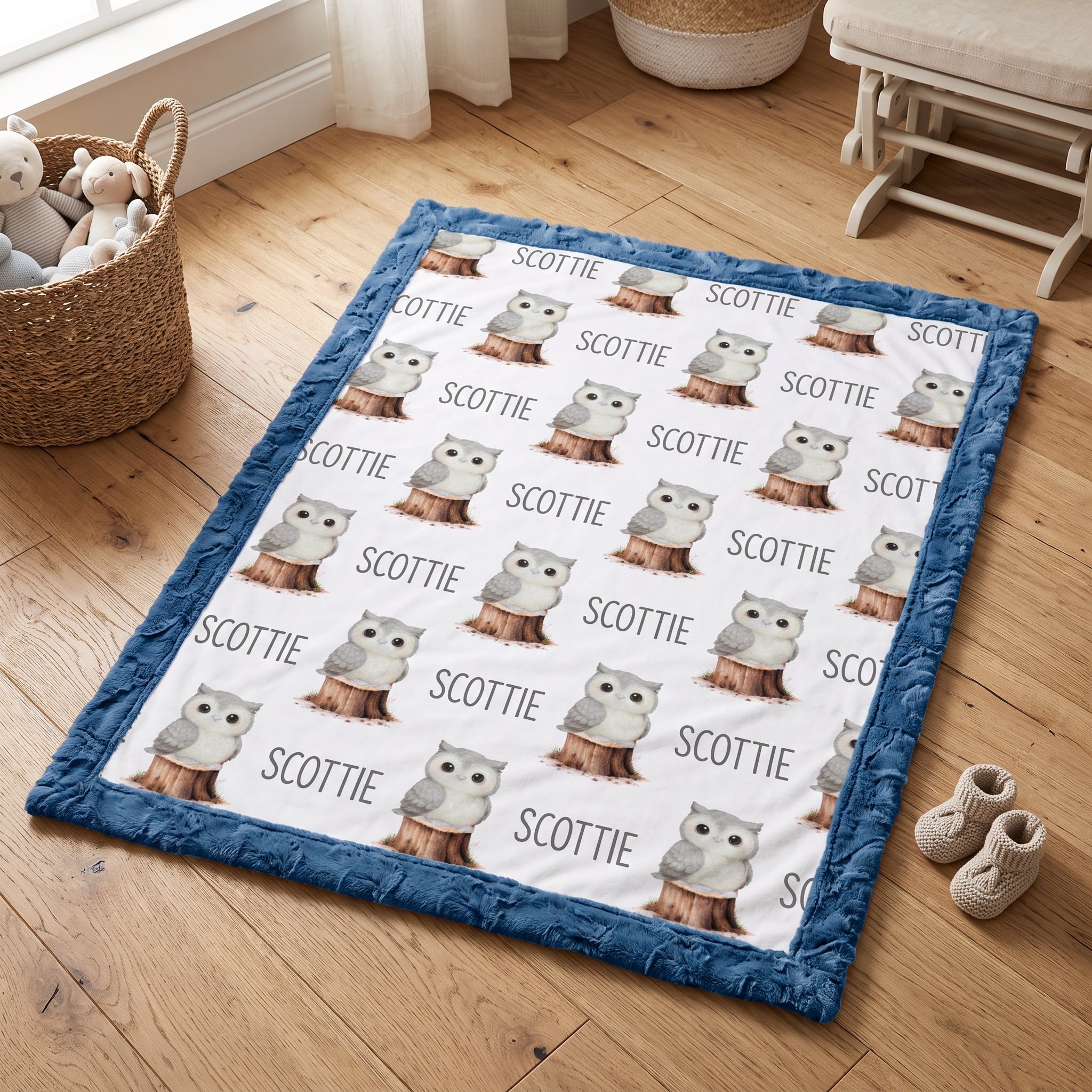 Personalized owl minky blanket with blue trim folded flat lay on wood floor