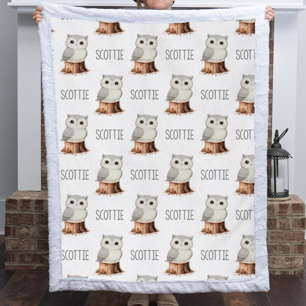 Personalized owl minky blanket with white sherpa back draped over nursery crib