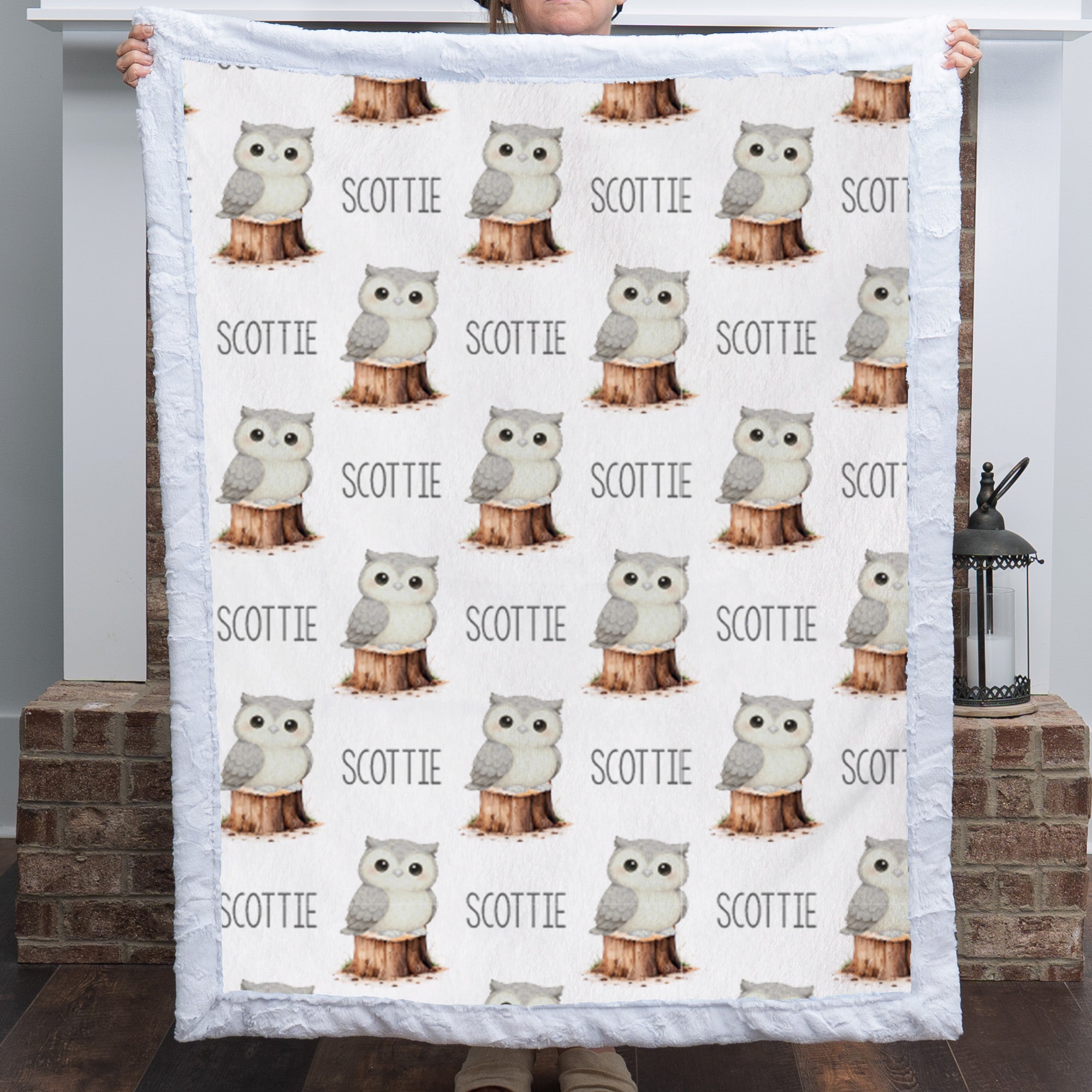 Personalized owl minky blanket with white sherpa back draped over nursery crib