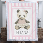 Personalized minky panda baby blanket with pink stripe border held up by fireplace