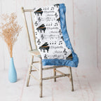 Personalized piano minky blanket with blue trim draped over vintage chair beside dried flowers
