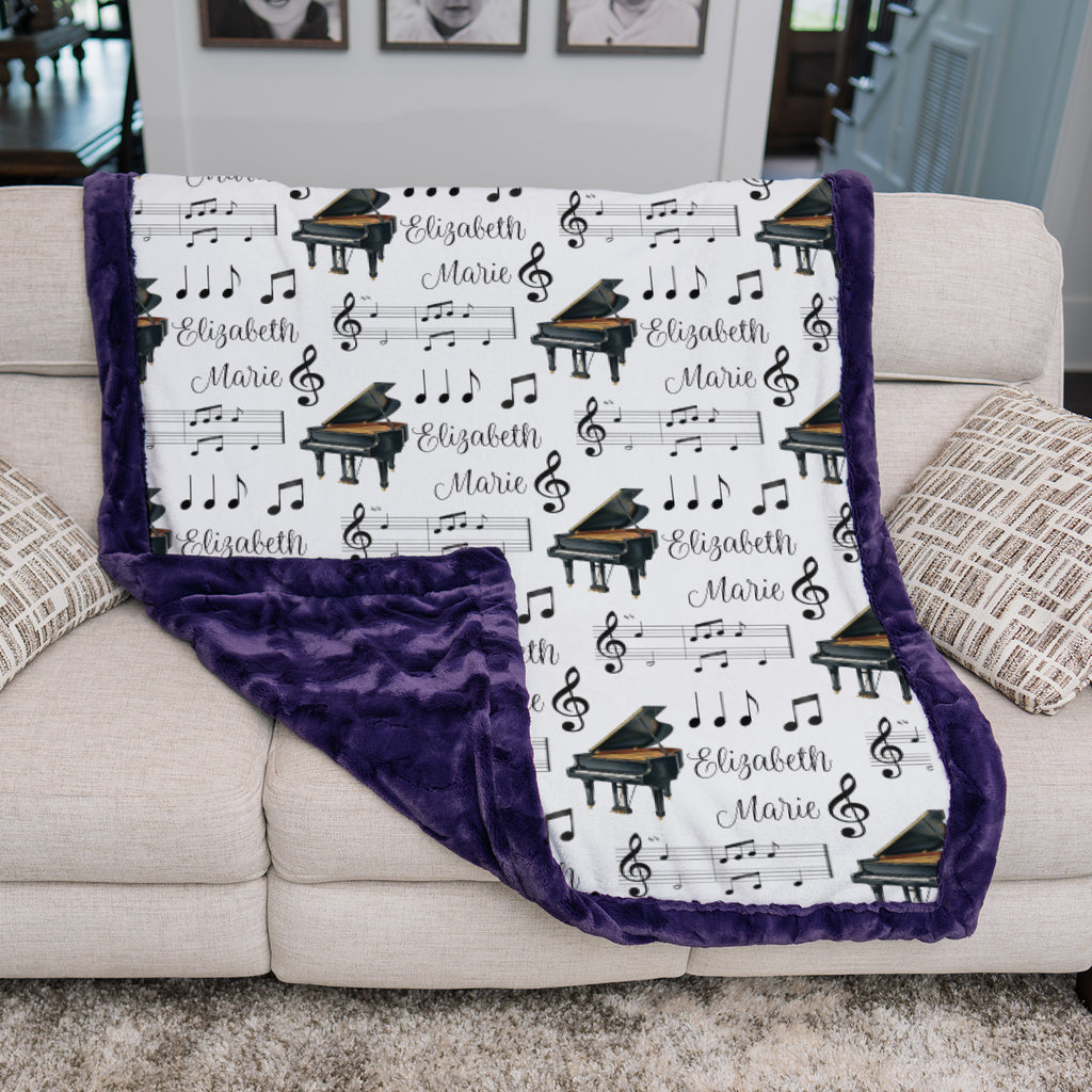 Personalized piano minky blanket with purple trim draped over couch in living room