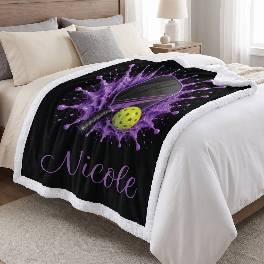 Purple pickleball blanket with plush white backing and personalized name Nicole, laid on a bed