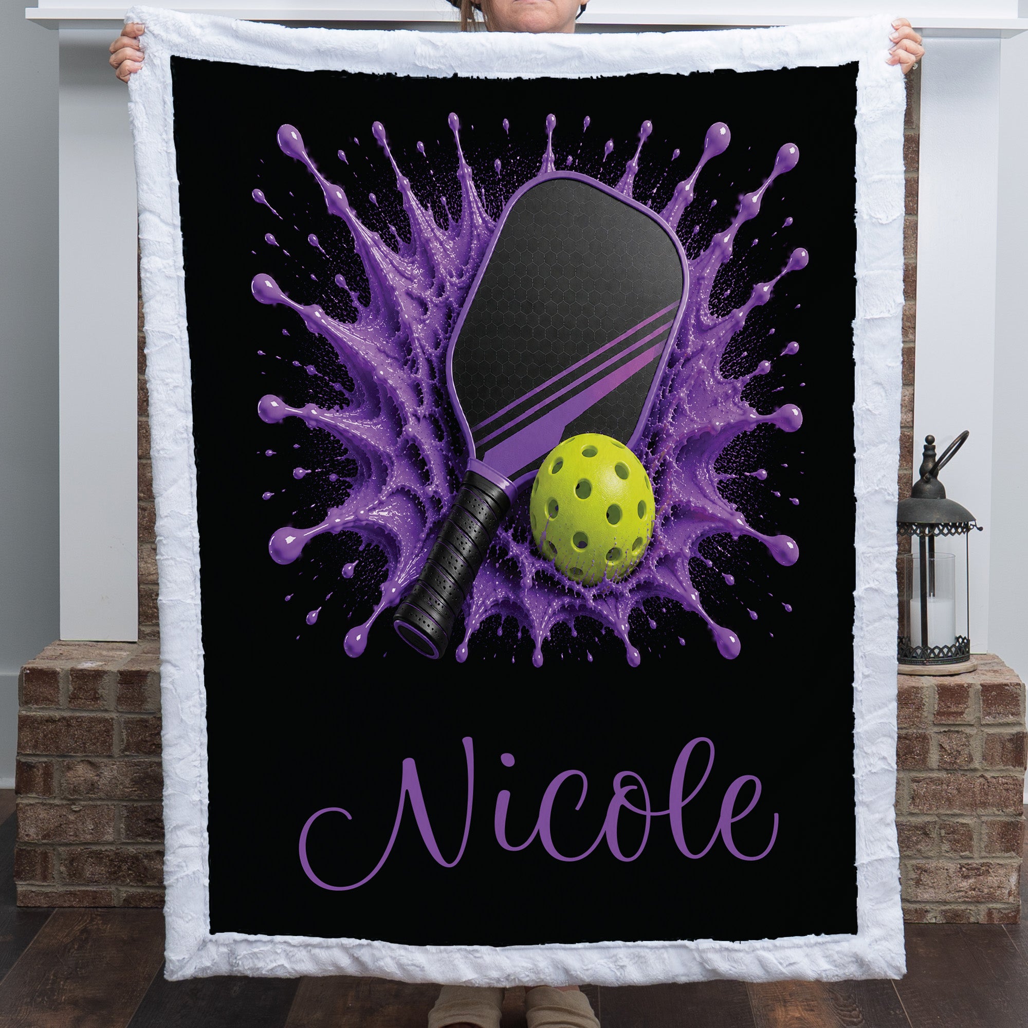 Personalized purple pickleball blanket with paddle and ball splash design and the name Nicole