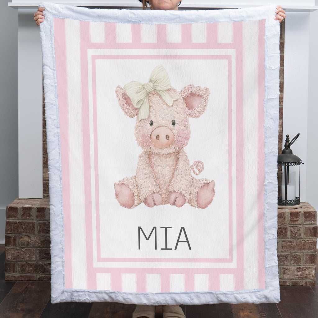 Personalized Luxe Cuddle Minky pig baby blanket with pink stripe border held up by fireplace
