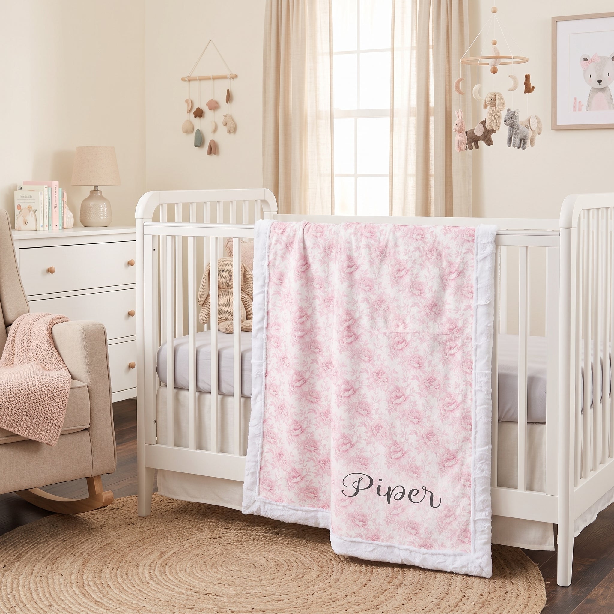 Personalized pink floral minky baby blanket draped over crib rail in nursery