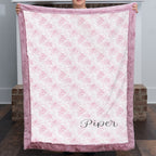 Personalized pink floral minky blanket with faux fur trim held up by fireplace mantel