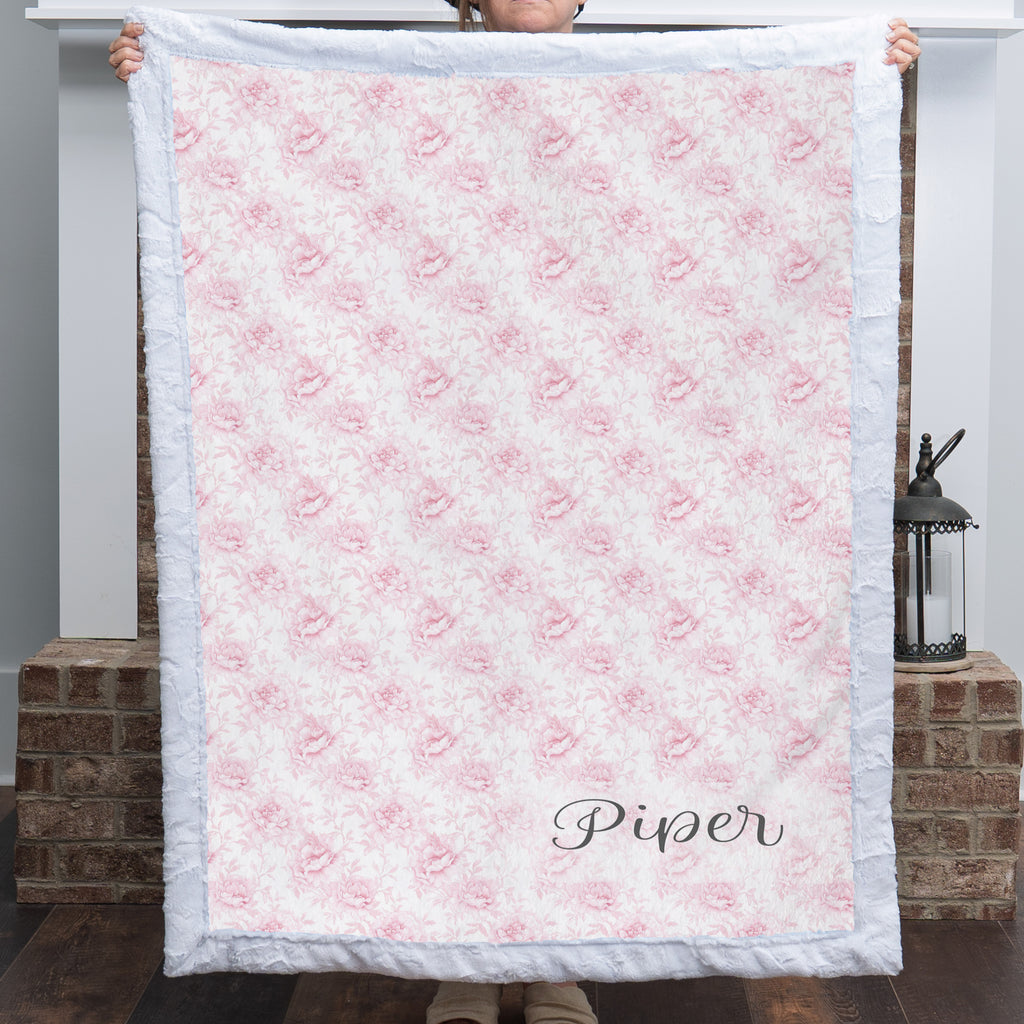 Personalized pink floral minky blanket displayed in front of white fireplace mantel