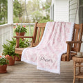 Personalized pink floral minky blanket draped over wooden porch swing outdoors