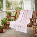 Personalized pink floral minky blanket draped over wooden porch swing outdoors