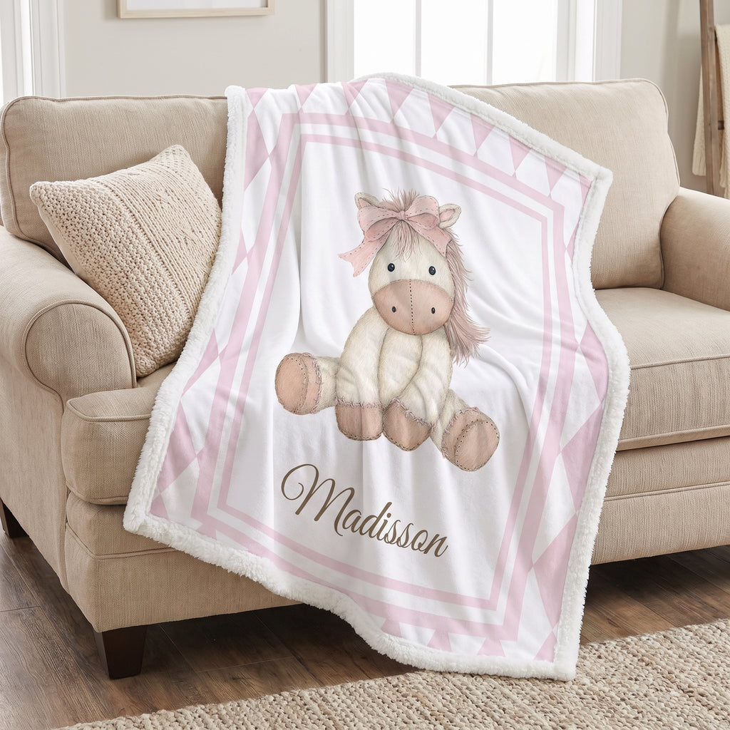 Personalized pink pony minky blanket draped over couch with white sherpa backing