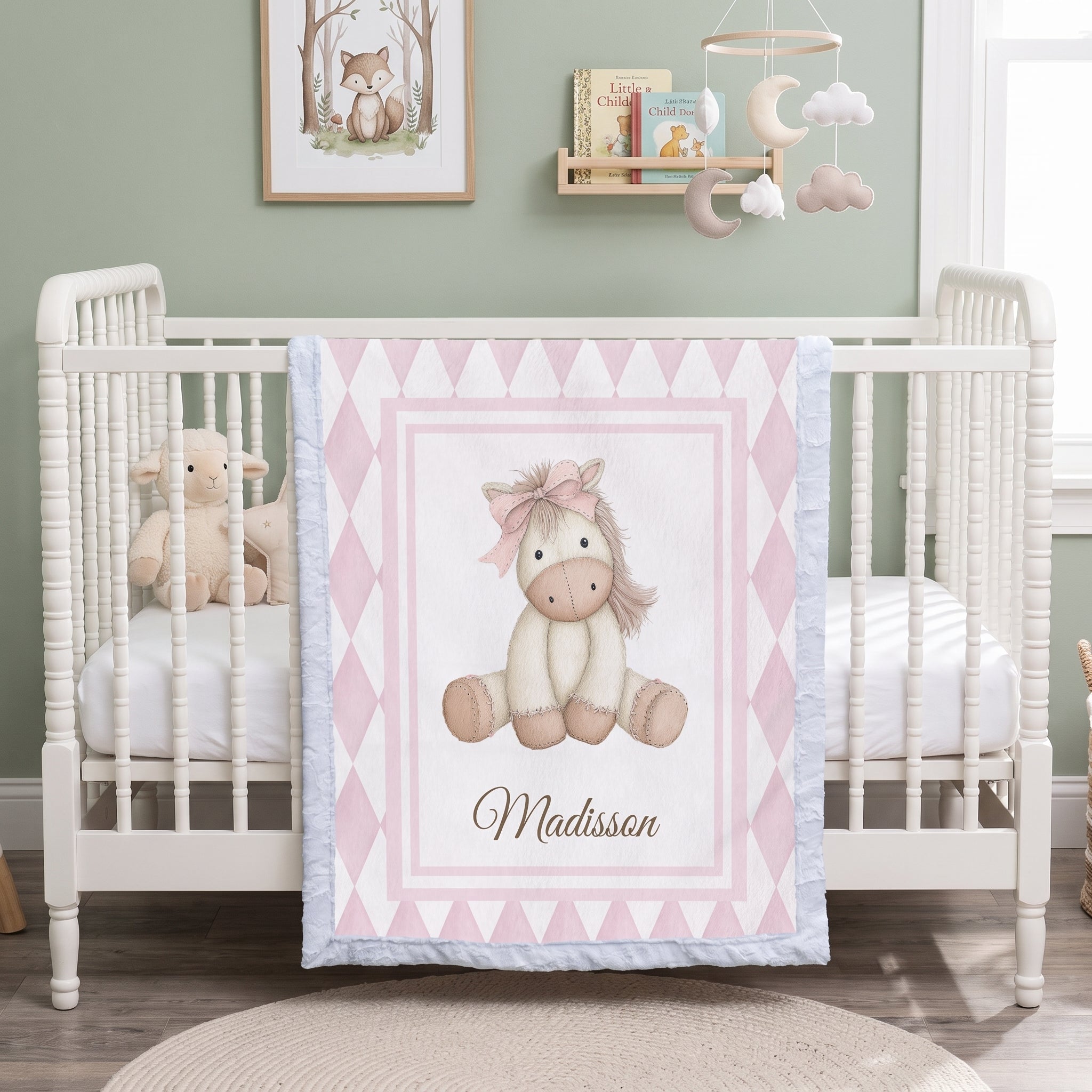 Personalized pink pony minky blanket draped on crib in woodland nursery