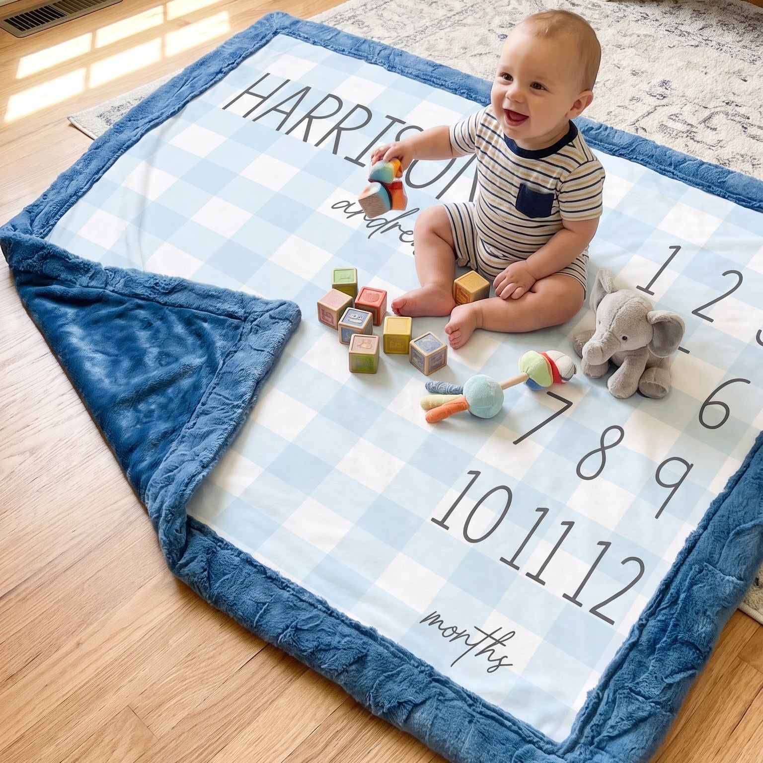 Baby boy lying on personalized plaid milestone blanket on nursery floor