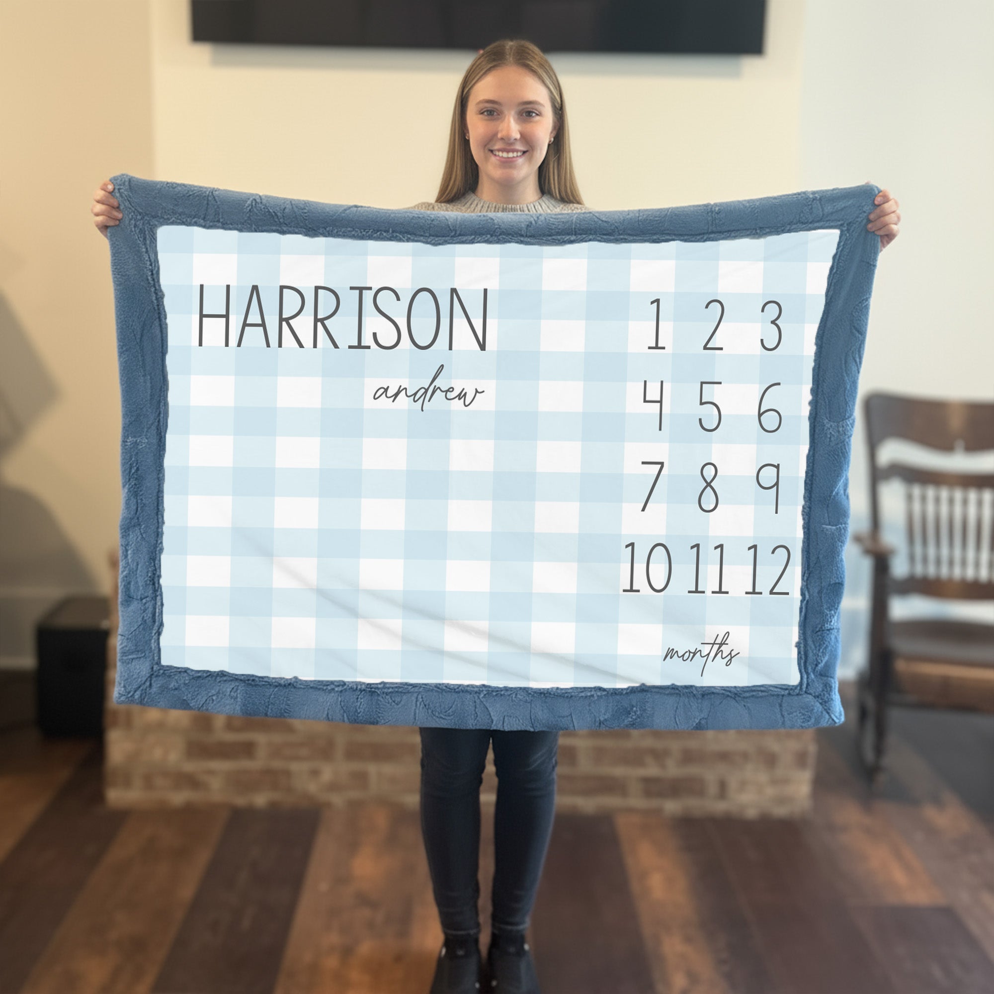 Personalized plaid milestone blanket flat lay with monthly markers and name