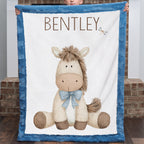 Boy holding personalized pony baby blanket with blue minky trim by brick fireplace