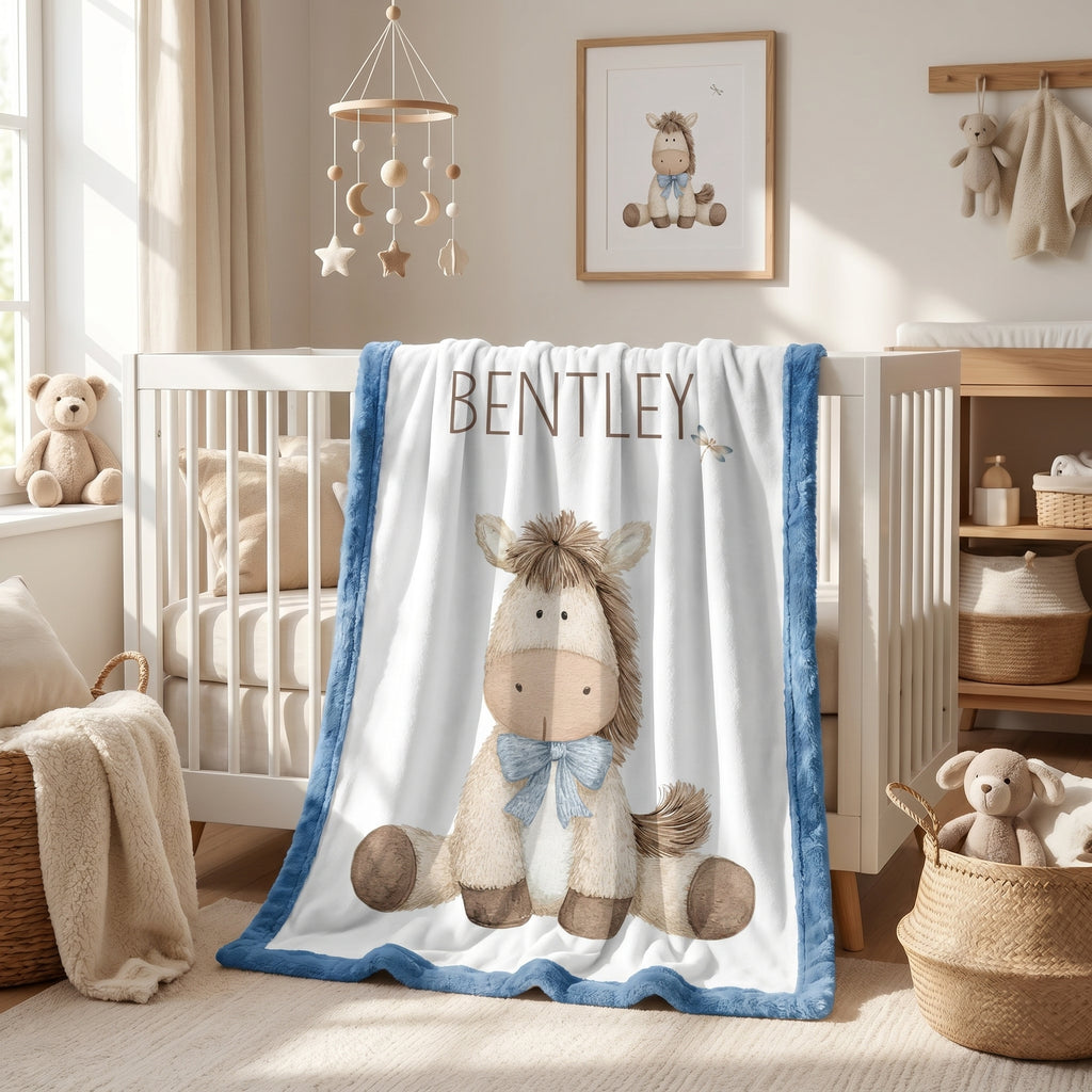 Personalized pony baby blanket with blue minky trim draped over nursery crib
