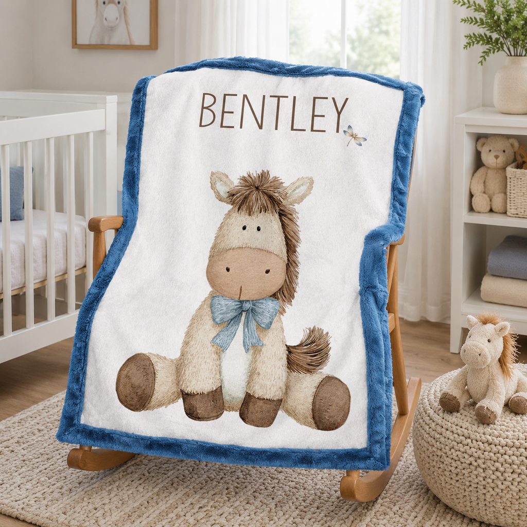 Personalized pony baby blanket with blue minky trim draped over wooden nursery rocking chair