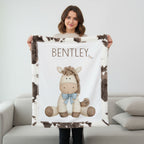 Woman holding personalized pony baby blanket with cow-print minky trim by fireplace mantel