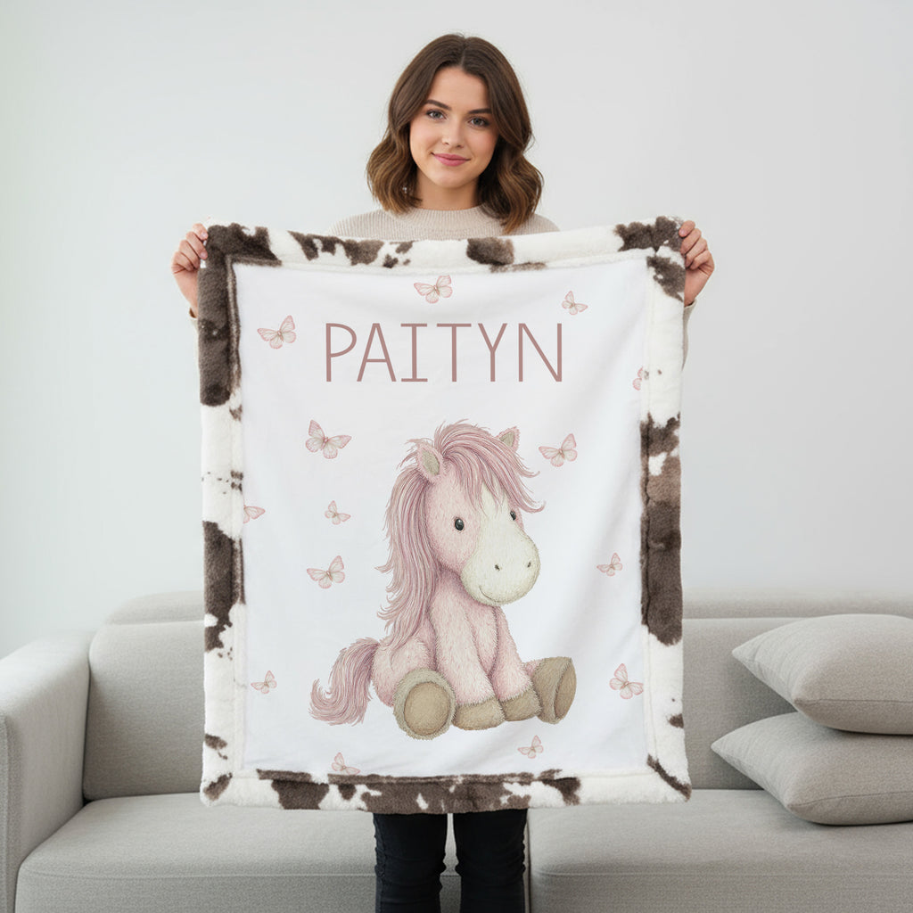 Woman holding personalized pony baby blanket with cow-print minky trim indoors
