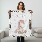 Woman holding personalized pony baby blanket with cow-print minky trim indoors
