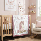 Personalized pony baby blanket with pink minky trim draped over nursery crib
