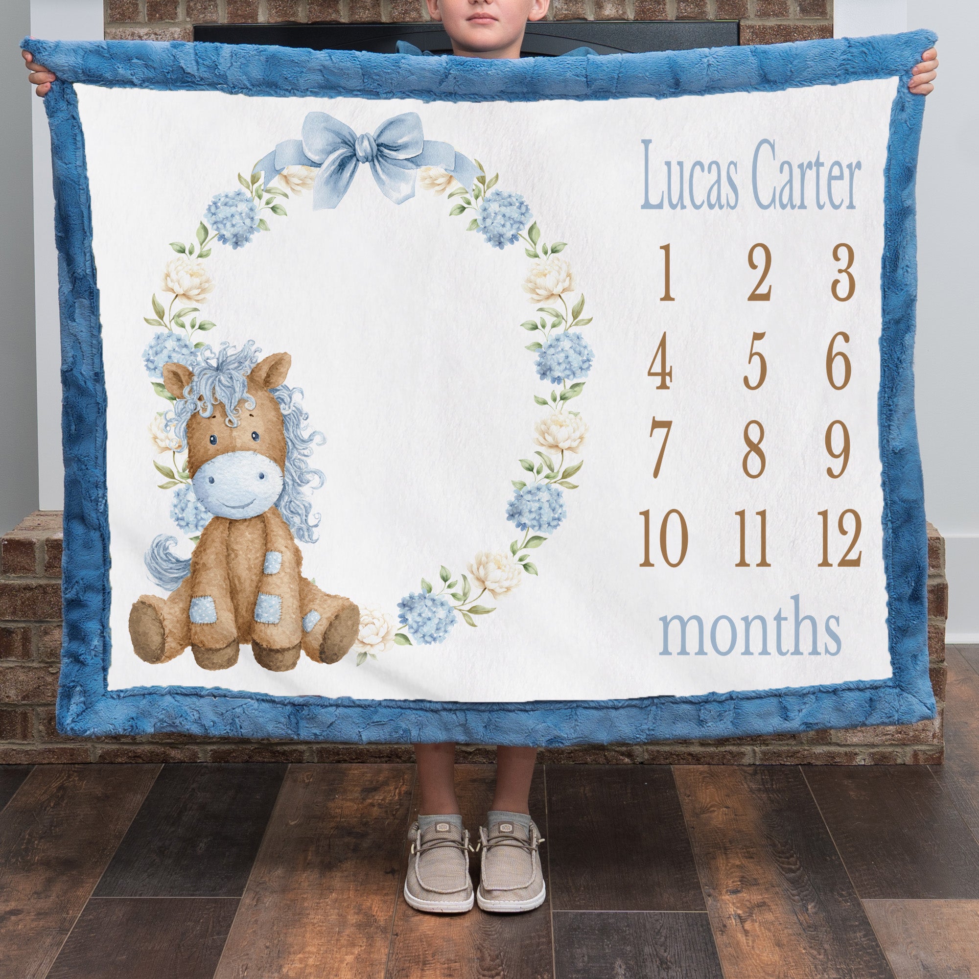 Personalized pony milestone minky blanket with blue trim shown by boy by fireplace