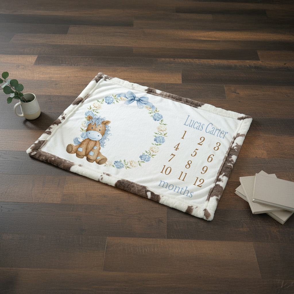 Personalized pony milestone minky blanket with blue trim held up by boy indoors