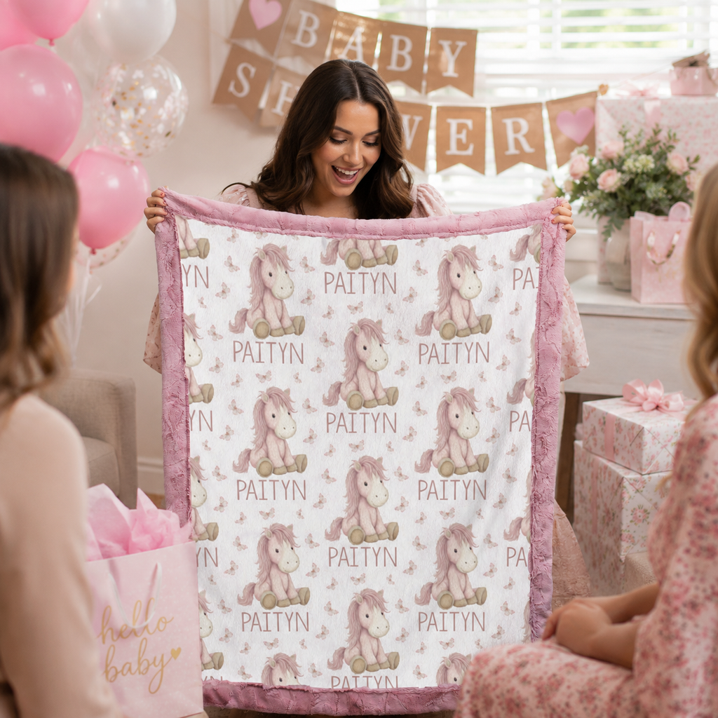 Woman holding personalized pony name blanket with pink minky trim at baby shower