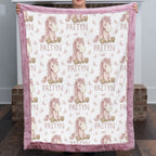 Woman holding personalized pony name blanket with pink minky trim by fireplace mantel