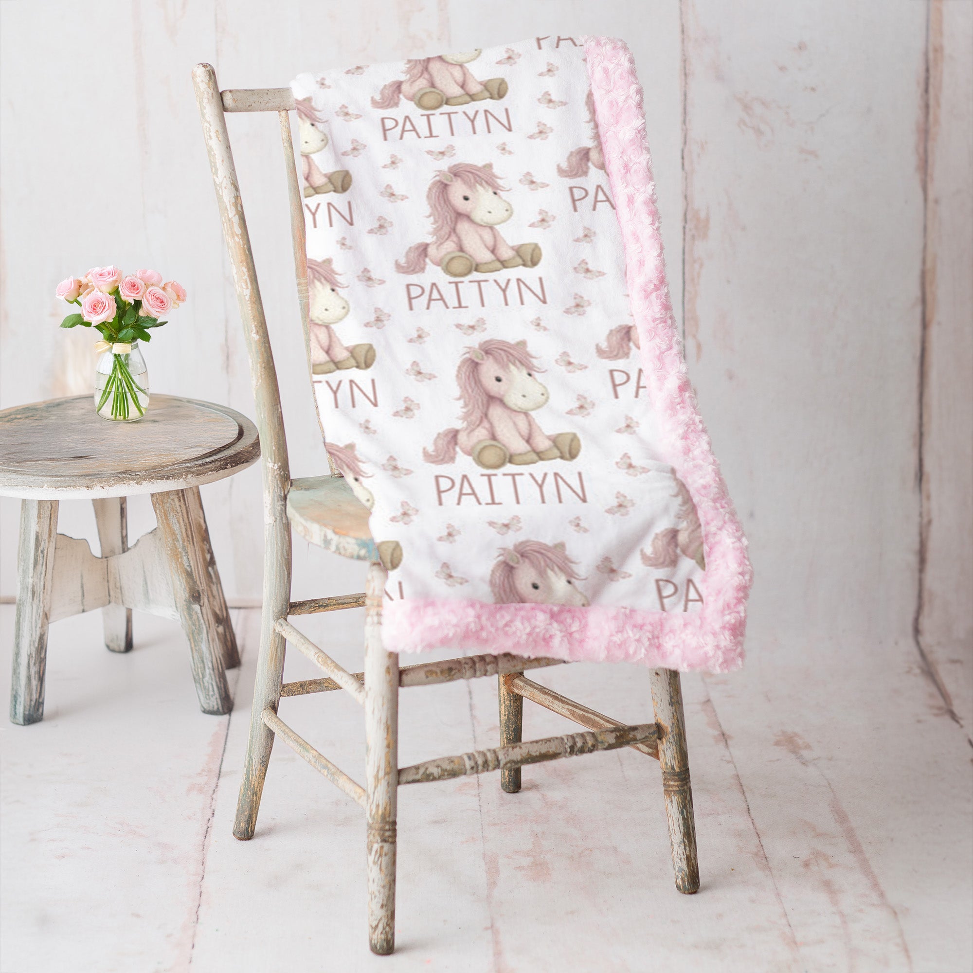 Personalized pony name blanket with pink minky trim draped over vintage rustic chair