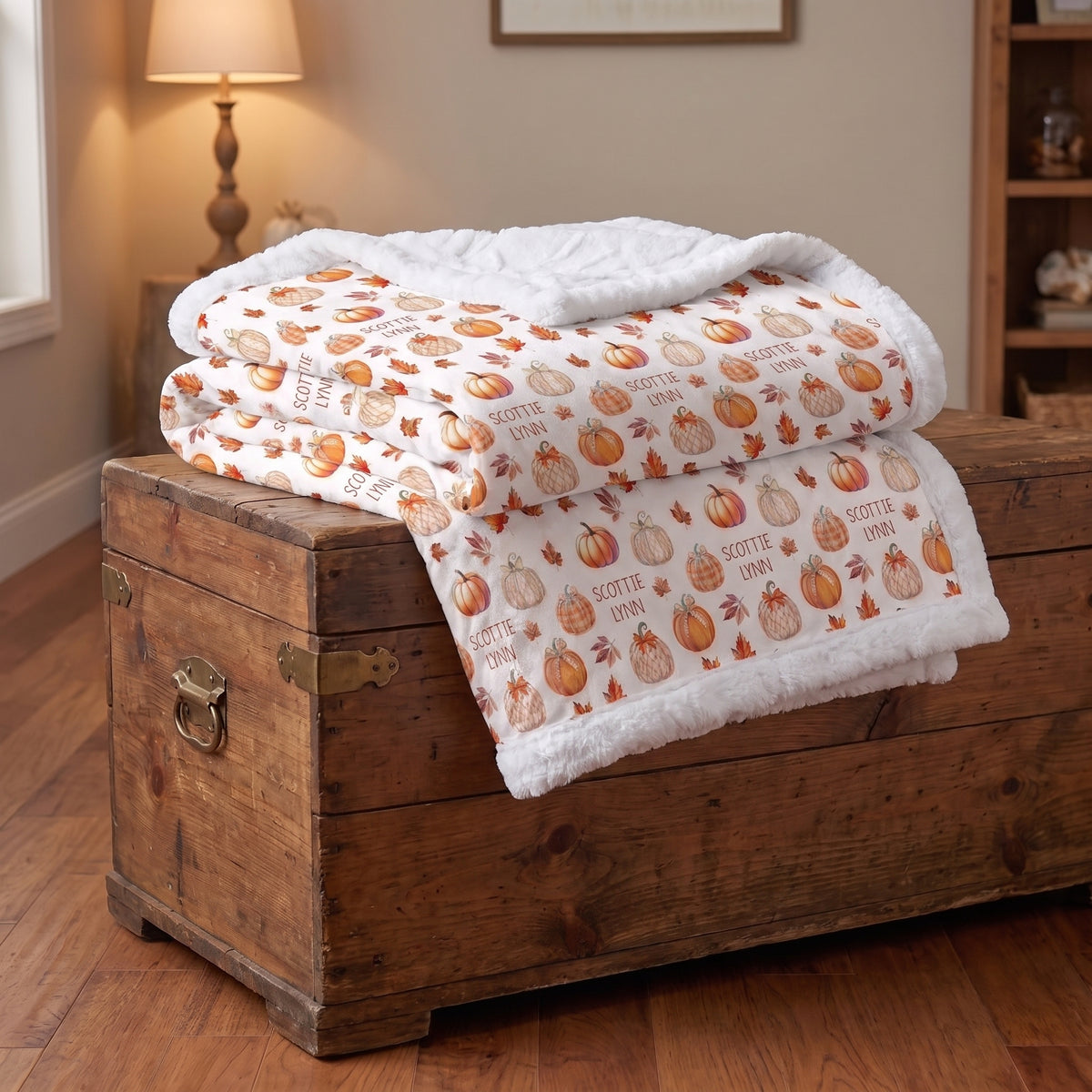Folded personalized pumpkin patch minky blanket stacked on wooden trunk, white faux fur trim