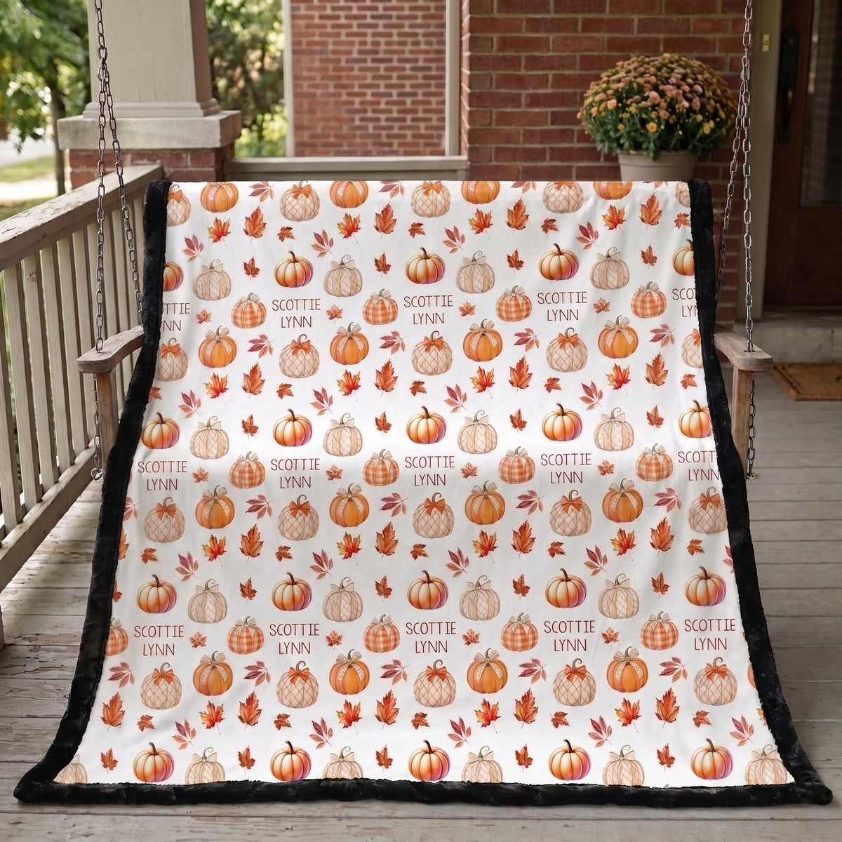 Personalized pumpkin patch minky blanket hanging on porch swing by brick house, black back