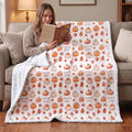 Personalized minky throw blanket with pumpkin patch print draped over lap while reading indoors
