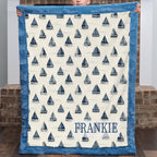 Personalized sailboat blanket with FRANKIE name, held up in front of brick fireplace