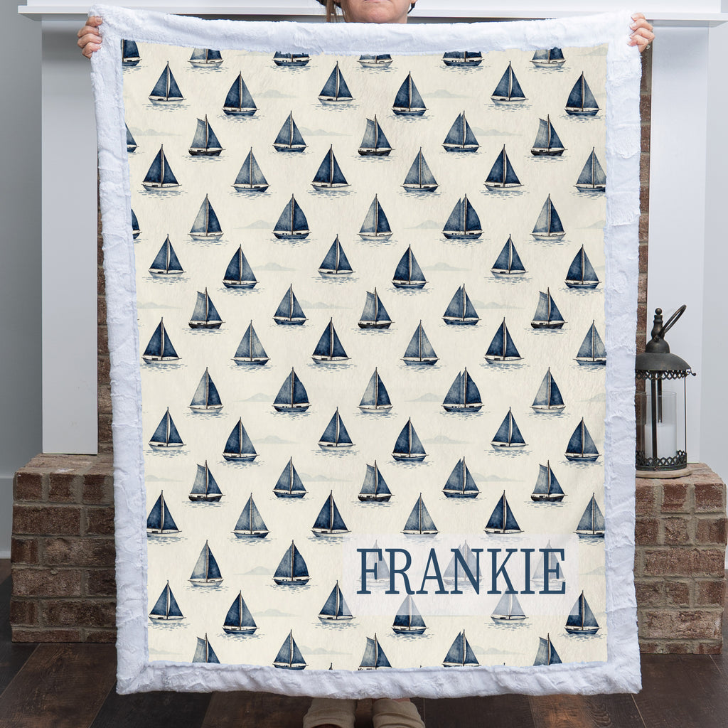 Personalized sailboat minky blanket with FRANKIE name held up by fireplace