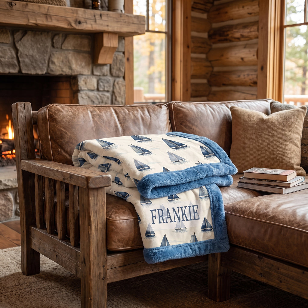 Personalized sailboat blanket folded on a leather couch in a cozy cabin living room