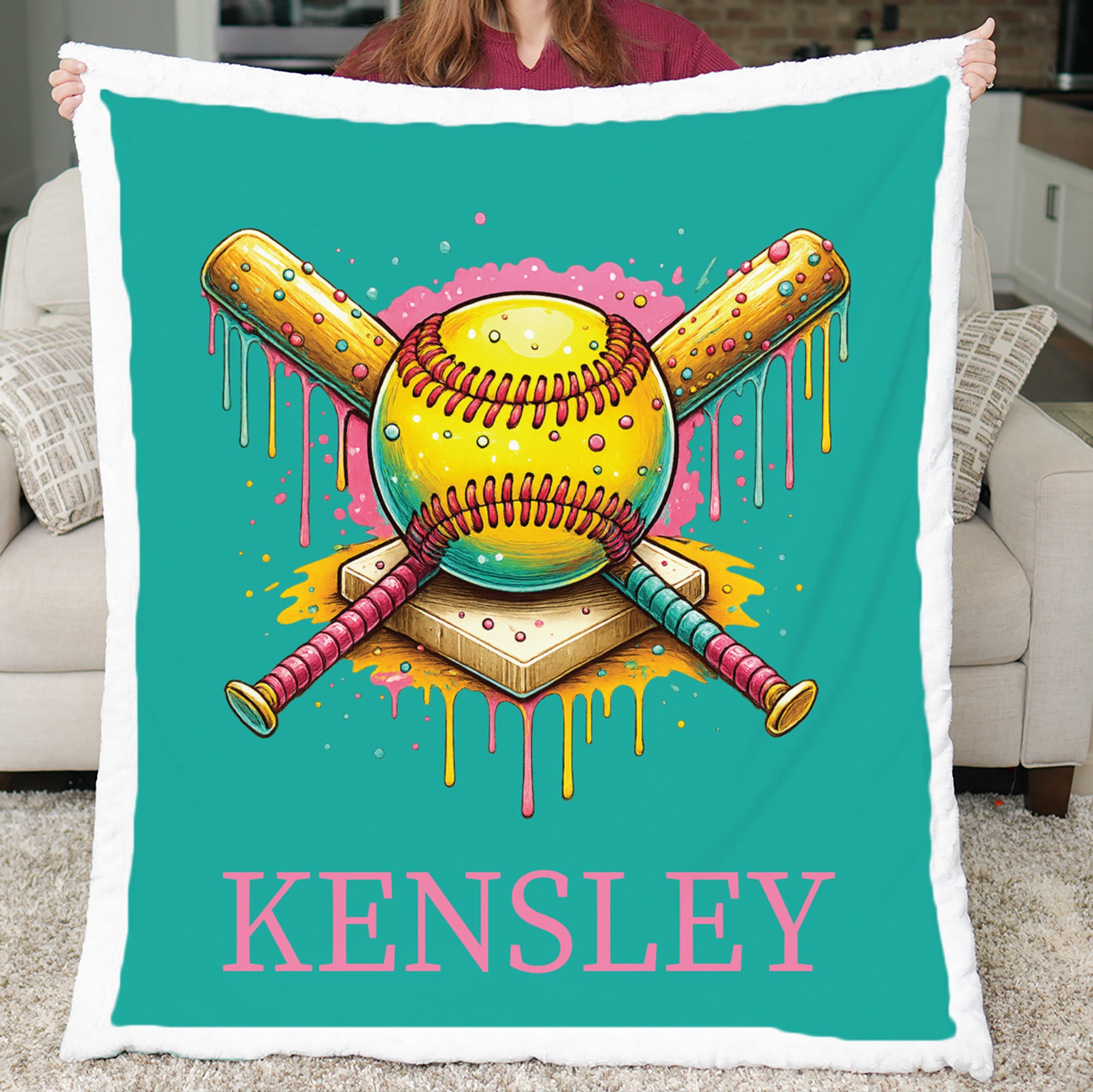 Woman holding personalized teal softball minky blanket with Kensley name in living room